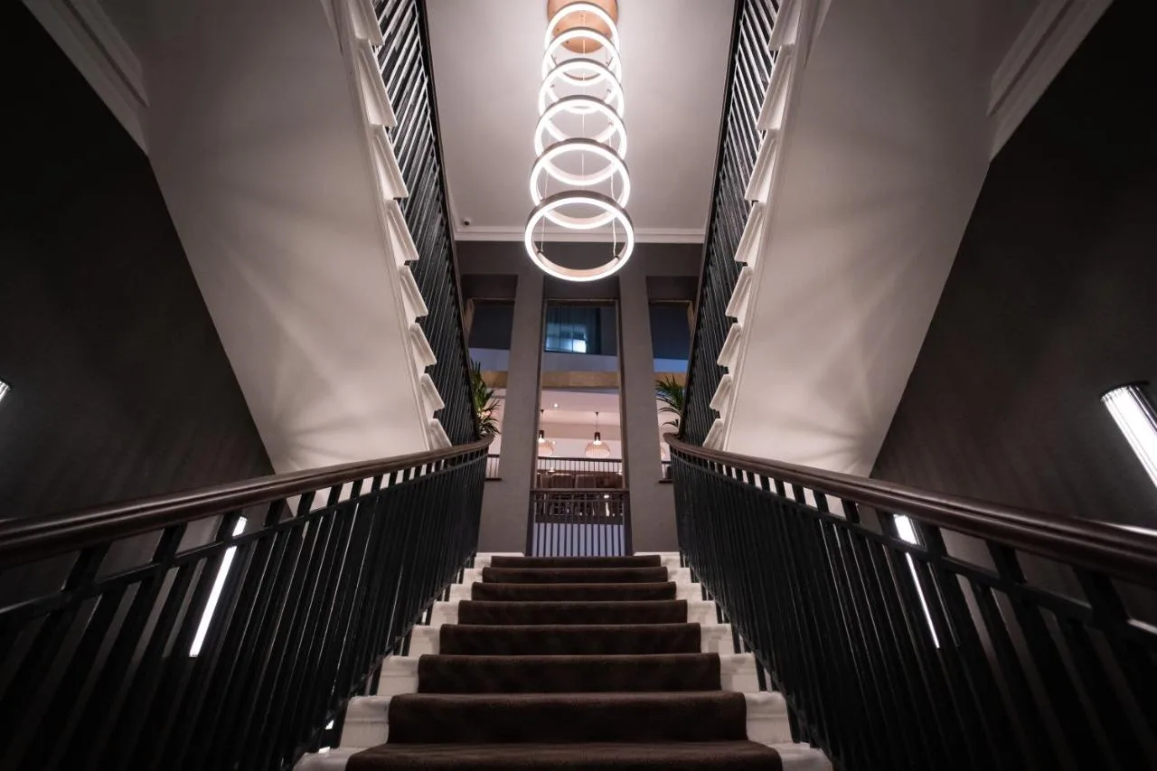 a staircase in a building with a chandelier at Clayton Hotel Glasgow City in Glasgow