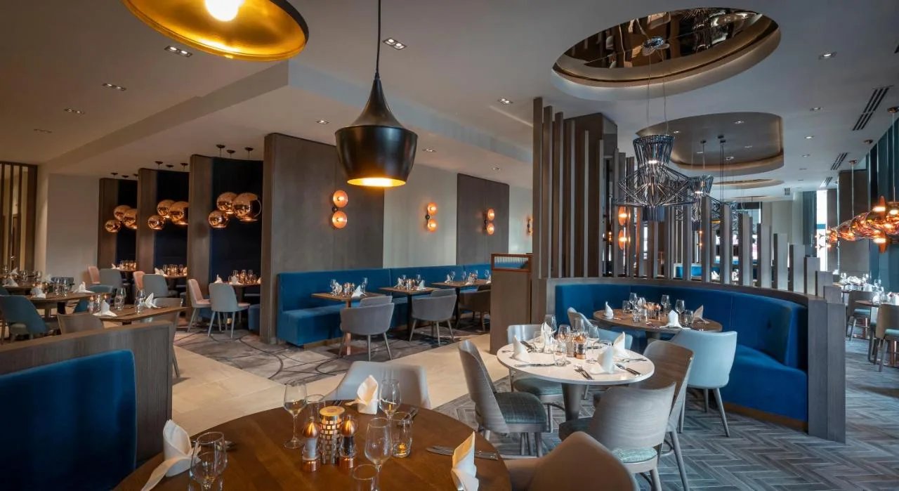 a dining room with tables and chairs and chandeliers at Clayton Hotel Glasgow City in Glasgow